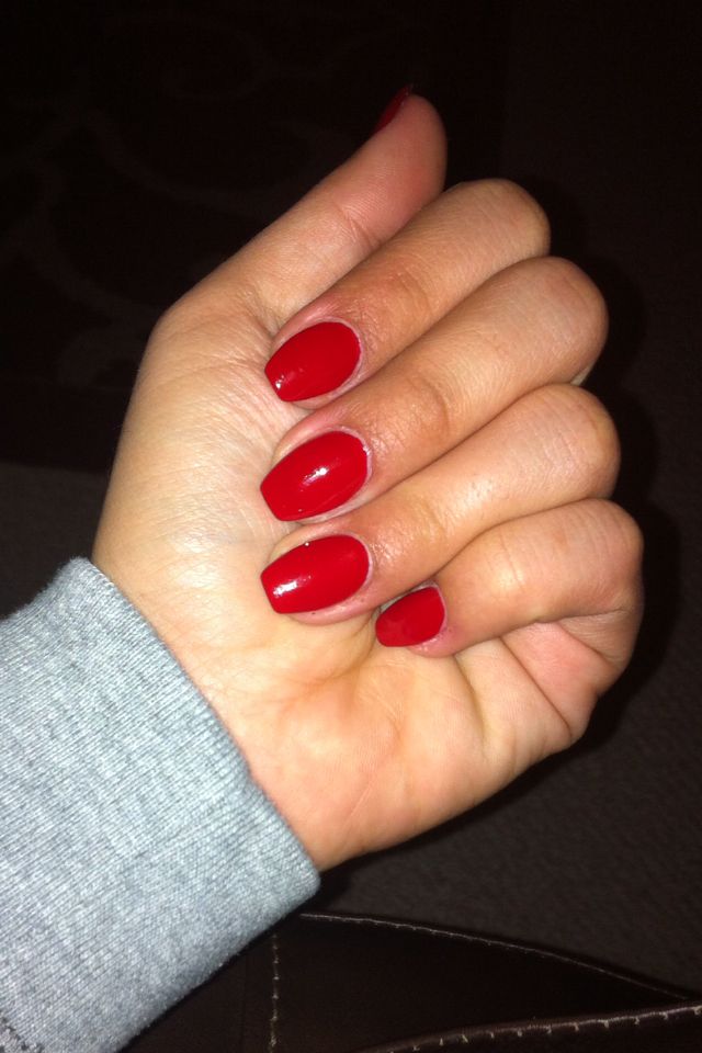 Intensive rote Nagellack-Farbe auf mittellangen ovalen Nägeln.